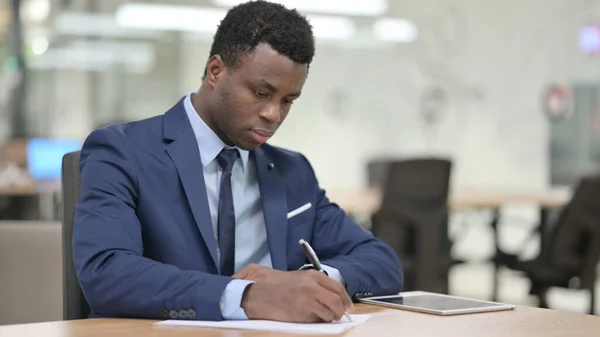 Afrikansk affärsman Skriva på papper i Office — Stockfoto