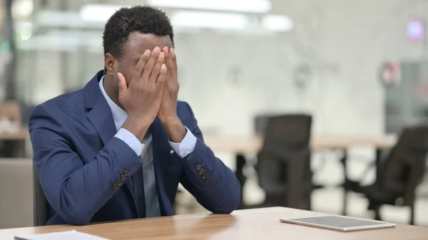 Napjatý africký podnikatel sedí v moderní kanceláři — Stock fotografie