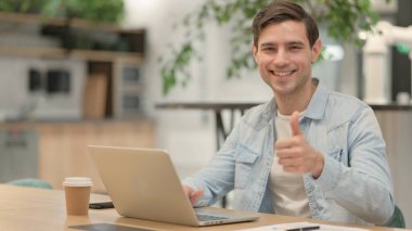 Dizüstü bilgisayarlı Genç Adam Başparmağını kaldırdı 