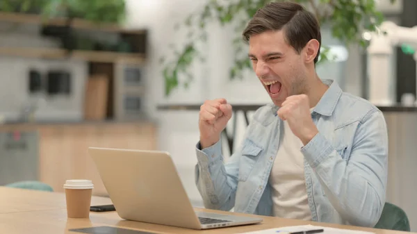 Giovane uomo di successo che festeggia sul computer portatile al lavoro — Foto Stock
