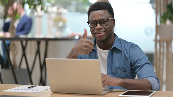 Afrikansk man visar tummen upp medan du arbetar på laptop — Stockfoto