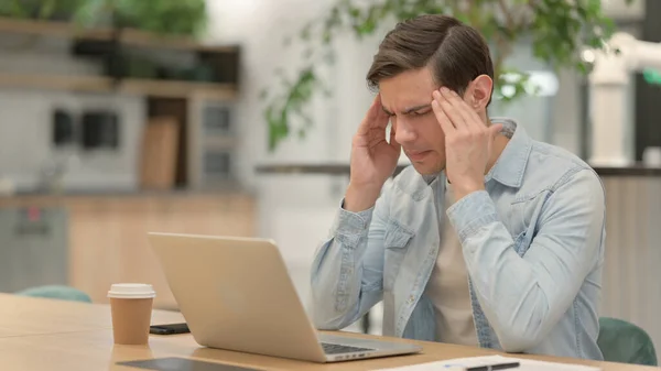 Junger Mann mit Laptop hat Kopfschmerzen — Stockfoto