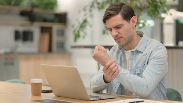 Jeune homme avec ordinateur portable ayant la douleur au poignet — Photo