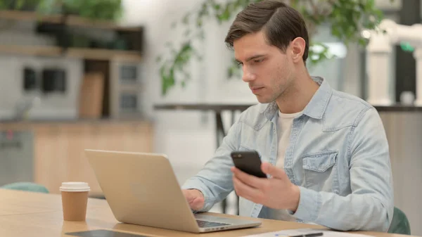 Young Man using Laptop and Smartphone at Work — Stock Photo, Image