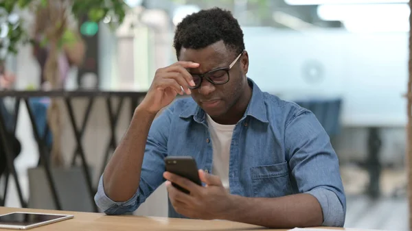 Zdenerwowany Afrykanin reaguje na stratę na smartfonie — Zdjęcie stockowe