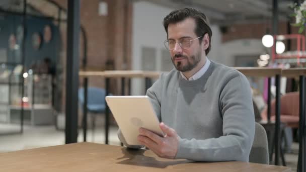 Ofiste otururken Tablet kullanan genç adam — Stok video