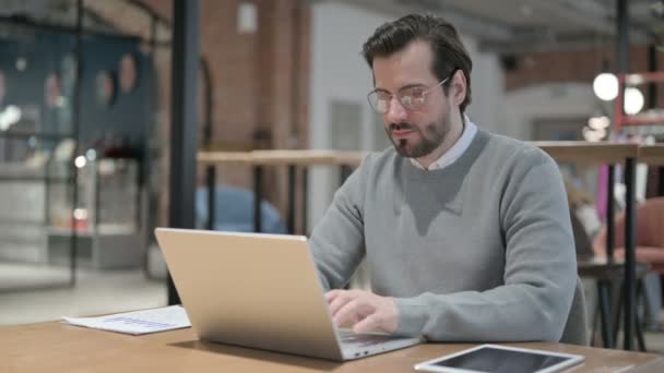 Junger Mann zeigt bei der Arbeit mit Laptop Daumen hoch — Stockvideo