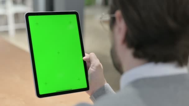 Man op zoek naar tablet met groene chroma scherm — Stockvideo