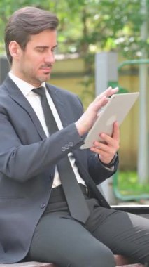 Genç İşadamı Bench 'te otururken Dijital Tablet Kullanıyor