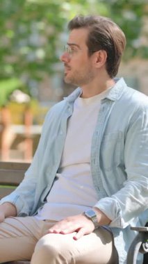 Park 'ta otururken gelişigüzel genç adam saati kontrol ediyor.