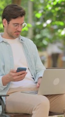 Smartphone ve Laptop üzerinde çalışan sıradan bir genç adam.