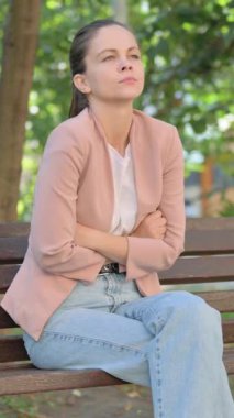 Park 'ta otururken öksüren genç kadın.