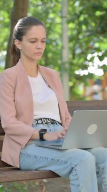 Banch 'ta dizüstü bilgisayar kullanan Genç Kadın Başparmaklarını Yana Koyuyor