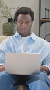 Evde dizüstü bilgisayar kullanan bilek ağrısı olan Afrikalı adam.