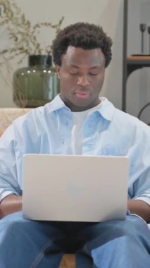 Afrikalı Adam kucağında dizüstü bilgisayarla kamerayı işaret ediyor