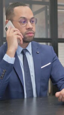 Dikey, Takım Elbiseli Adam Ofiste telefonda konuşuyor.