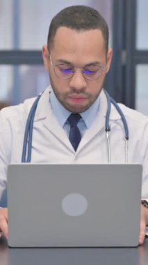 Dikey, Karışık Irk Doktoru Ofiste Dizüstü bilgisayarda çalışıyor