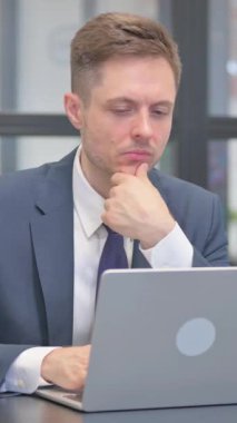 Dikey video, Düşünceli Olgun Yetişkin İş Adamı Laptop 'ta Okuyor