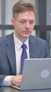 Dikey video, Yetişkin İş Adamı Dizüstü bilgisayarda çalışırken Kamerayı Gösteriyor