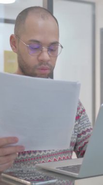 Genç İspanyol Adam Belgeler ve Laptop üzerinde çalışıyor, dikey video