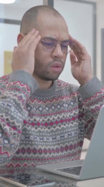 Genç İspanyol adamın iş yerinde baş ağrısı var, dikey video.