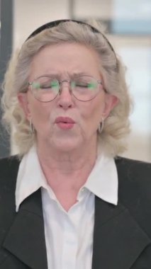 Baş ağrısı ve dikey videosu olan kıdemli iş kadınının portresi