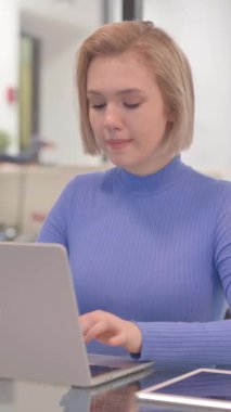 Dişi ağrılı genç kadın ofiste dizüstü bilgisayarda çalışıyor, dikey video.