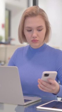 Laptop 'ta Çalışan ve Akıllı Telefon Kullanan Genç Kadın, dikey video