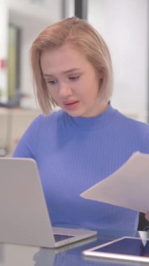 Sözleşmeyi Okurken ve Dizüstü bilgisayar kullanırken Genç Kadın Üzgün Hissediyor, dikey video