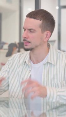 Ofiste oturan kızgın yaratıcı genç adam, dikey video