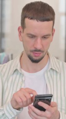 Telefonla konuşan yaratıcı genç adamın portresi, dikey video