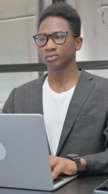 Laptop 'ta çalışan dikey, genç Afrikalı adam