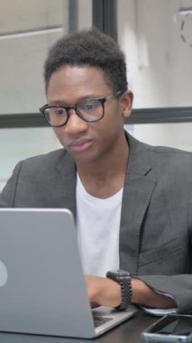 Dikey, Genç Afrikalı Adam Bilgisayarda çalışırken kamerayı işaret ediyor