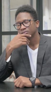 Dikey, Dalgın Genç Afrikalı Adam çalışırken beyin fırtınası yapıyor.