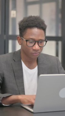 Dikey, şoke olmuş Afrikalı Amerikalı Adam Bilgisayarda çalışırken kameraya bakıyor