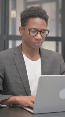 Dikey, Afrikalı Amerikalı Adam Bilgisayarda çalışırken kamerayı işaret ediyor