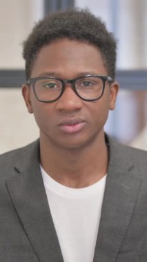 Ofisinde baş ağrısı olan Afro-Amerikan bir adamın dikey portresi.