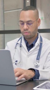 Laptop 'ta çalışırken kamerada gülümseyen İspanyol doktor, dikey video