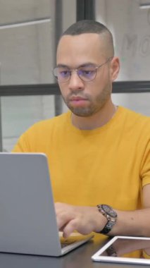 Ofiste dizüstü bilgisayar kullanan Öksüren İspanyol Adam, dikey video