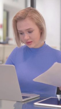 Sözleşmeyi Okurken ve Dizüstü bilgisayar kullanırken Genç Kadın Üzgün Hissediyor, dikey video