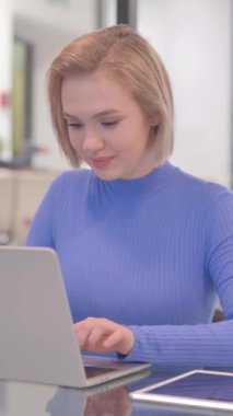 Ofiste Dizüstü bilgisayarda çalışırken Başparmakları Düşük Genç Kadın, dikey video