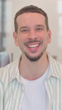 Telefondaki başarıyı kutlayan yaratıcı genç adamın portresi, dikey video