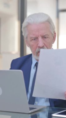 Eski İşadamı Kontrat Okurken Üzülüyor ve Dizüstü bilgisayar kullanıyor, dikey video