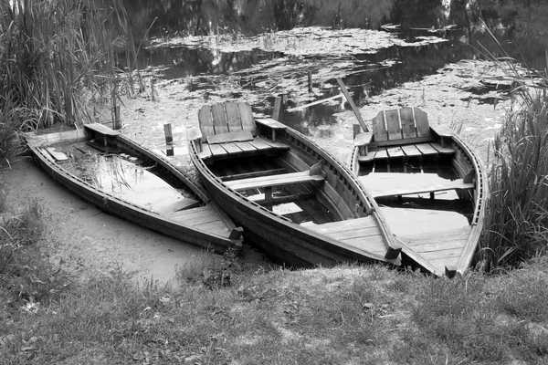 Black and white landscape with three wooden boats on river — Stock Photo, Image