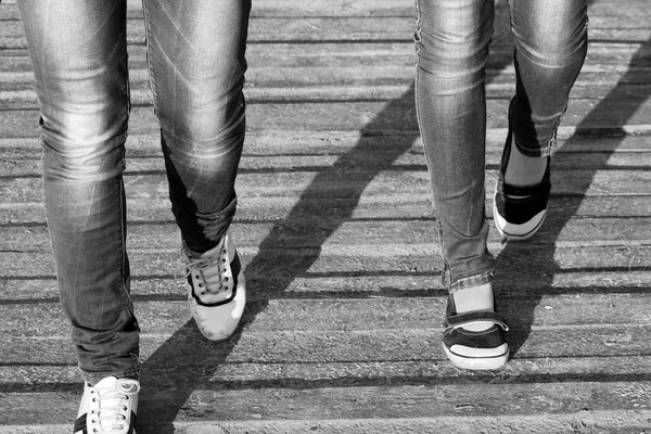 Kvinnan jeans och sneaker skor på trä bakgrund, svartvit Foto — Stockfoto