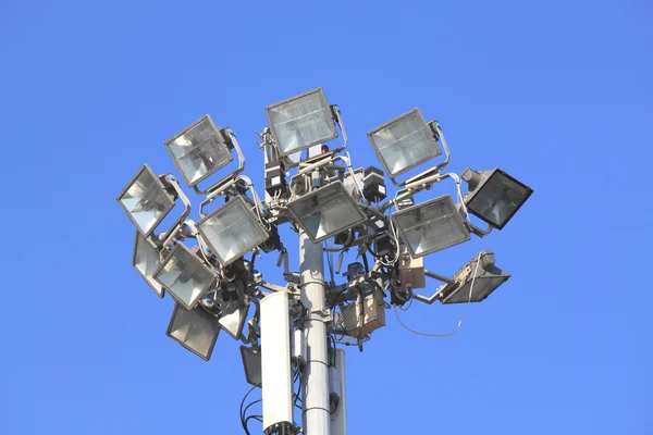 Beaucoup de projecteurs lumineux sur un poteau contre le ciel bleu — Photo