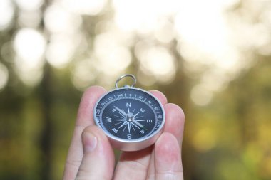 Turizmin sembolü olarak Bokeh ile birlikte doğal arka plan üzerinde eski klasik navigasyon pusulası, pusula ile seyahat ve pusula ile açık hava aktiviteleri