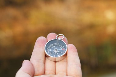 Pusula ile turizmin sembolü olarak doğal arka planda eski klasik navigasyon pusulası, pusula ile seyahat ve pusula ile dış aktiviteler