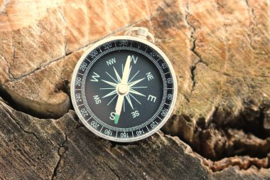 Pusula ile turizmin sembolü olarak doğal ahşap arka planda yuvarlak pusula, pusula ile seyahat ve pusula ile açık hava aktiviteleri