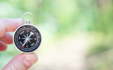 Pusula ile turizmin, pusula ile seyahat etmenin ve pusula ile açık hava aktivitelerinin sembolü olarak, doğal arka planda eski klasik navigasyon pusulası bulunmakta